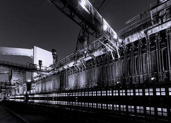 Low angle view of illuminated factory against sky at night