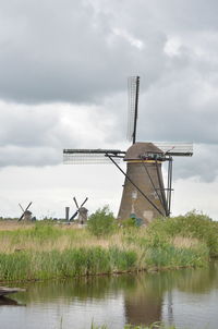 Windmill on field against cloudy sky