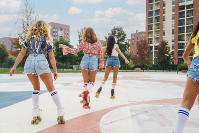 Friends roller skating and dancing together at sports court