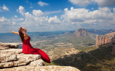 Rear view of woman standing on mountain against sky