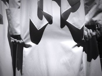 Close-up of hands hanging against the sky