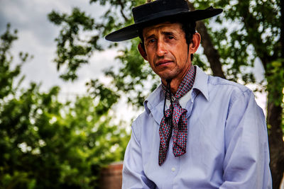 Man wearing hat against trees