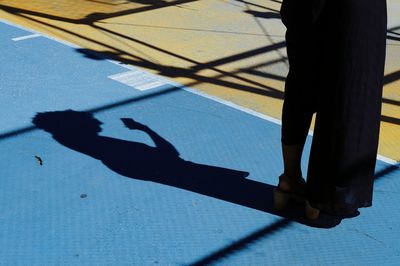 Shadow and low section of young woman checking her smart phone