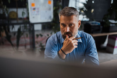 Senior man working at contemporary office, typing on keyboard