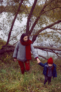 Mom and son go through the autumn forest next to the river
