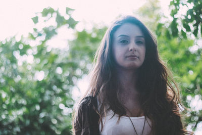 Portrait of young woman against trees