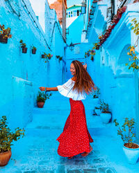 Girl in a red skirt dancing in the middle of the street in the blue city of chefchaouen in morocco