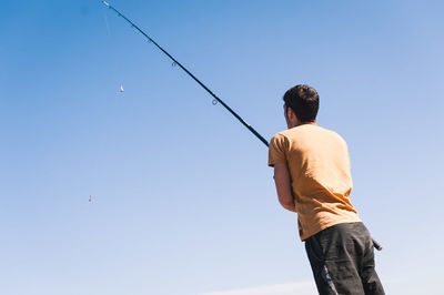 Rear view of man standing against clear sky