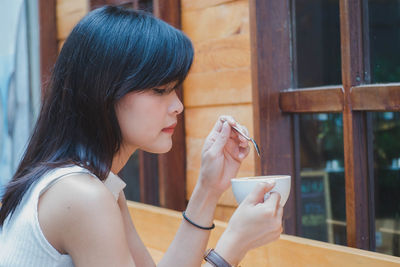 Close-up of woman having coffee against window