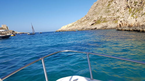 Sailboat sailing in sea against clear blue sky