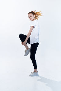 Full length portrait of young woman standing against white background