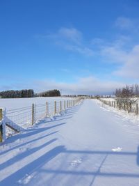 Snow covered landscape against blue sky