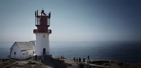 Lighthouse by sea against sky