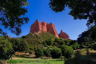 View of rock formation and trees against sky