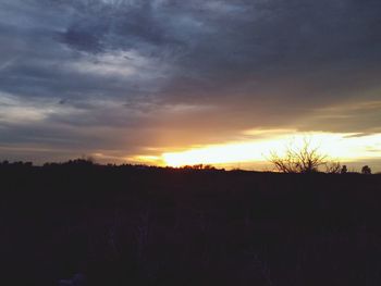 Scenic view of silhouette field against sky at sunset