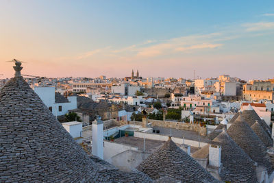 Buildings in city against sky during sunset