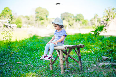 Full length of boy sitting on seat in field