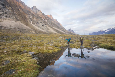 Reflection of hikers holding up poles in akshayak pass