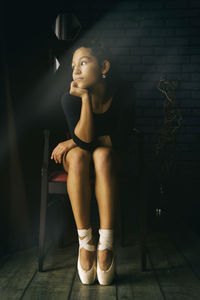 A young gentle and thoughtful ballerina poses in the interior and at the window