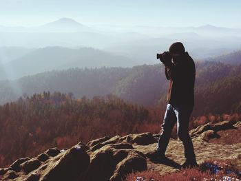 Professional photographer takes photos with mirror camera on peak of rock. professional photographer