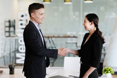 Business colleagues shaking hands in office