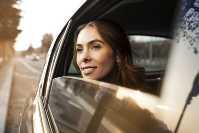 Smiling young woman looking out of car window