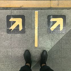 Low section of person standing on road sign