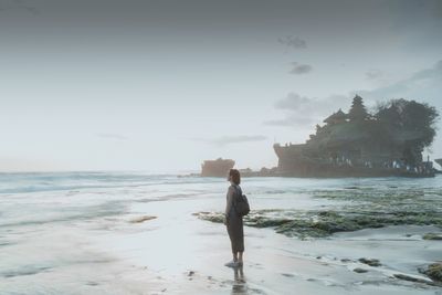 Full length of man standing on rock at beach against sky