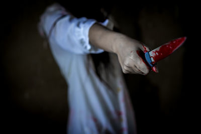 Low section of evil woman holding knife covered with blood