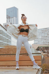 Fashionable woman standing against buildings in city