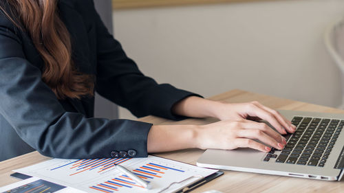 Midsection of woman using mobile phone while sitting on table