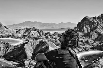Rear view of man looking at rocks against sky
