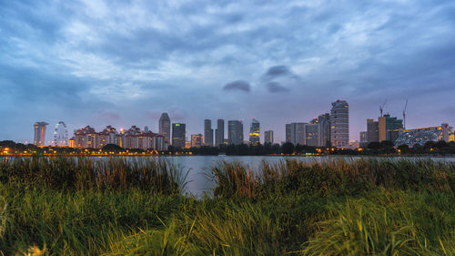 City at waterfront against cloudy sky