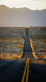 View of country road along landscape against sky during sunset