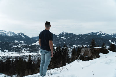 Rear view of man standing on snowcapped mountain
