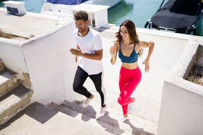 Full length of couple running on steps at harbor