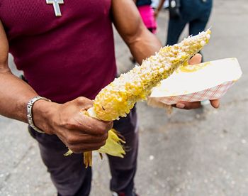 Midsection of man holding corncob on street
