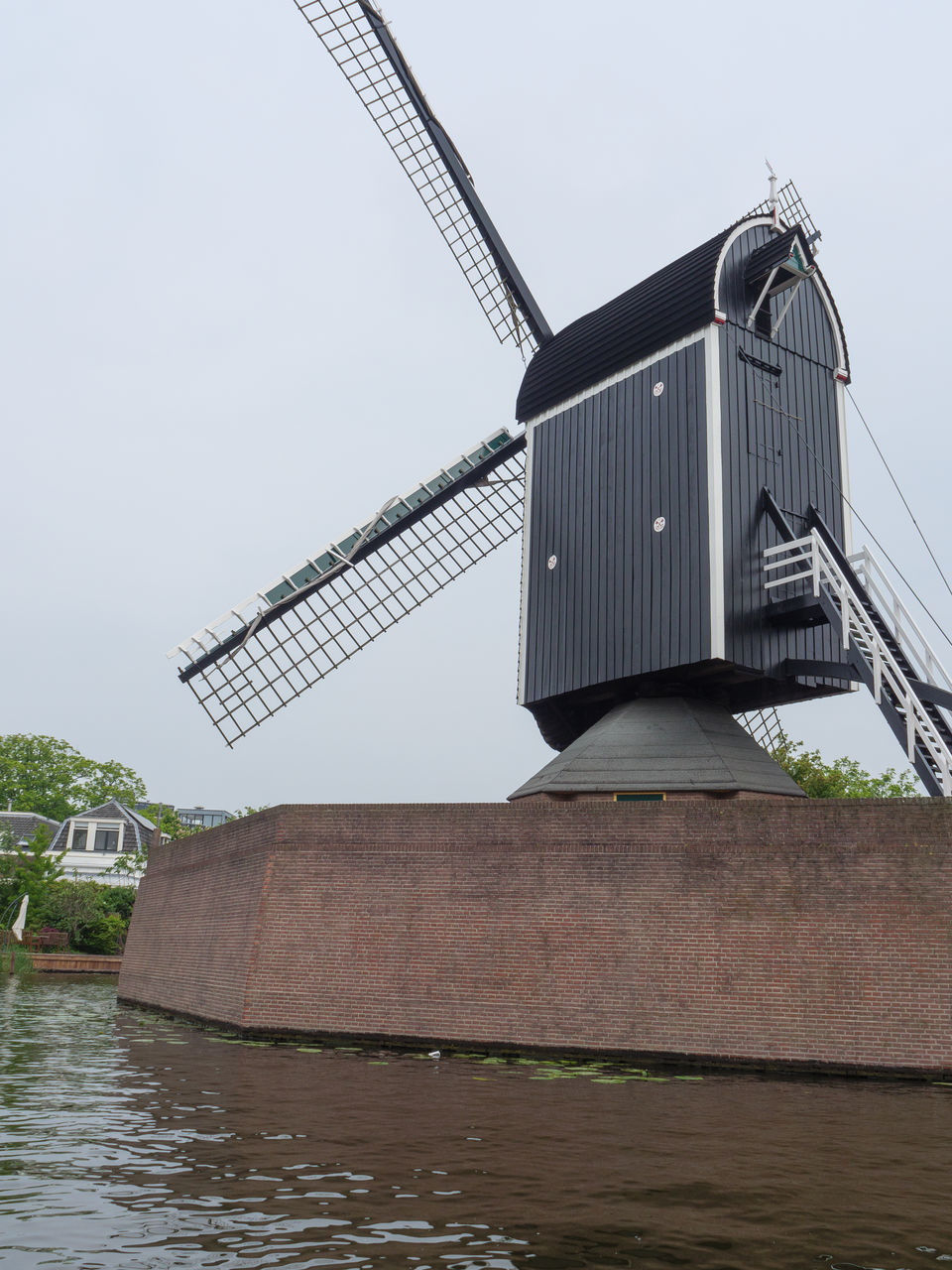 LOW ANGLE VIEW OF TRADITIONAL WINDMILL BY WATER AGAINST SKY