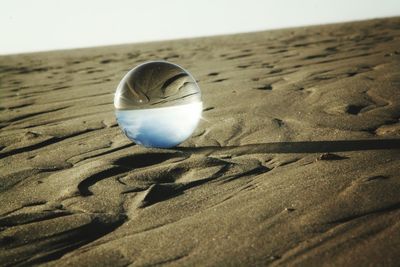 Close-up of ball on sand at beach against sky