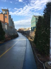 Street by houses against sky in city