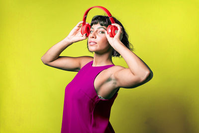 Portrait of young woman standing against yellow wall