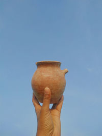 Midsection of person holding ice cream against blue sky