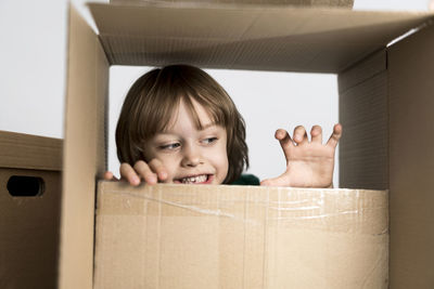 Cute toddler boy playing in cardboard box at new home.