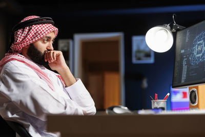 Side view of young man using mobile phone while sitting at home