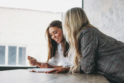 Young woman using smart phone while sitting on table