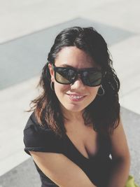 High angle portrait of mid adult woman wearing sunglasses while sitting outdoors
