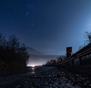 Road amidst trees against sky at night