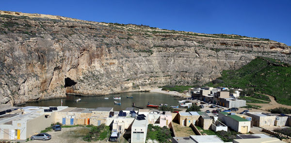 High angle view of buildings and mountains against clear blue sky