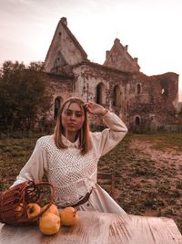 Portrait of young woman holding umbrella against built structure