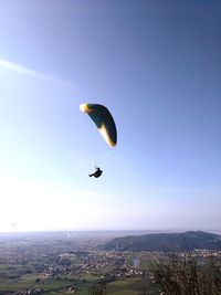 Low angle view of person paragliding against clear blue sky during sunny day